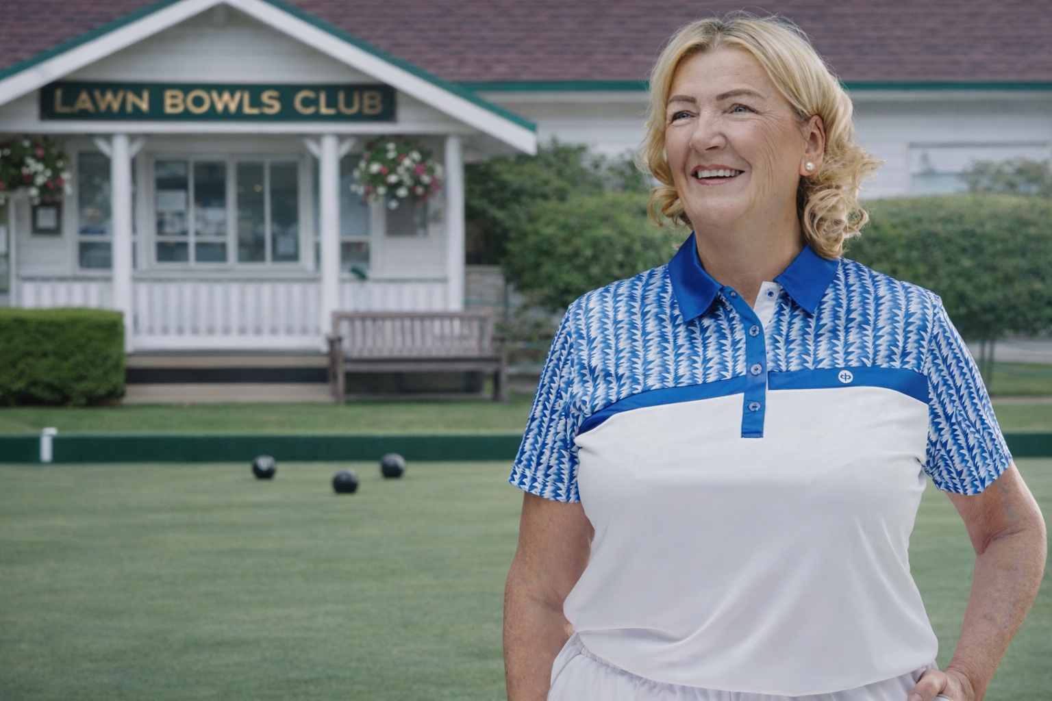 Woman standing on a lawn bowling green with a club house in the background